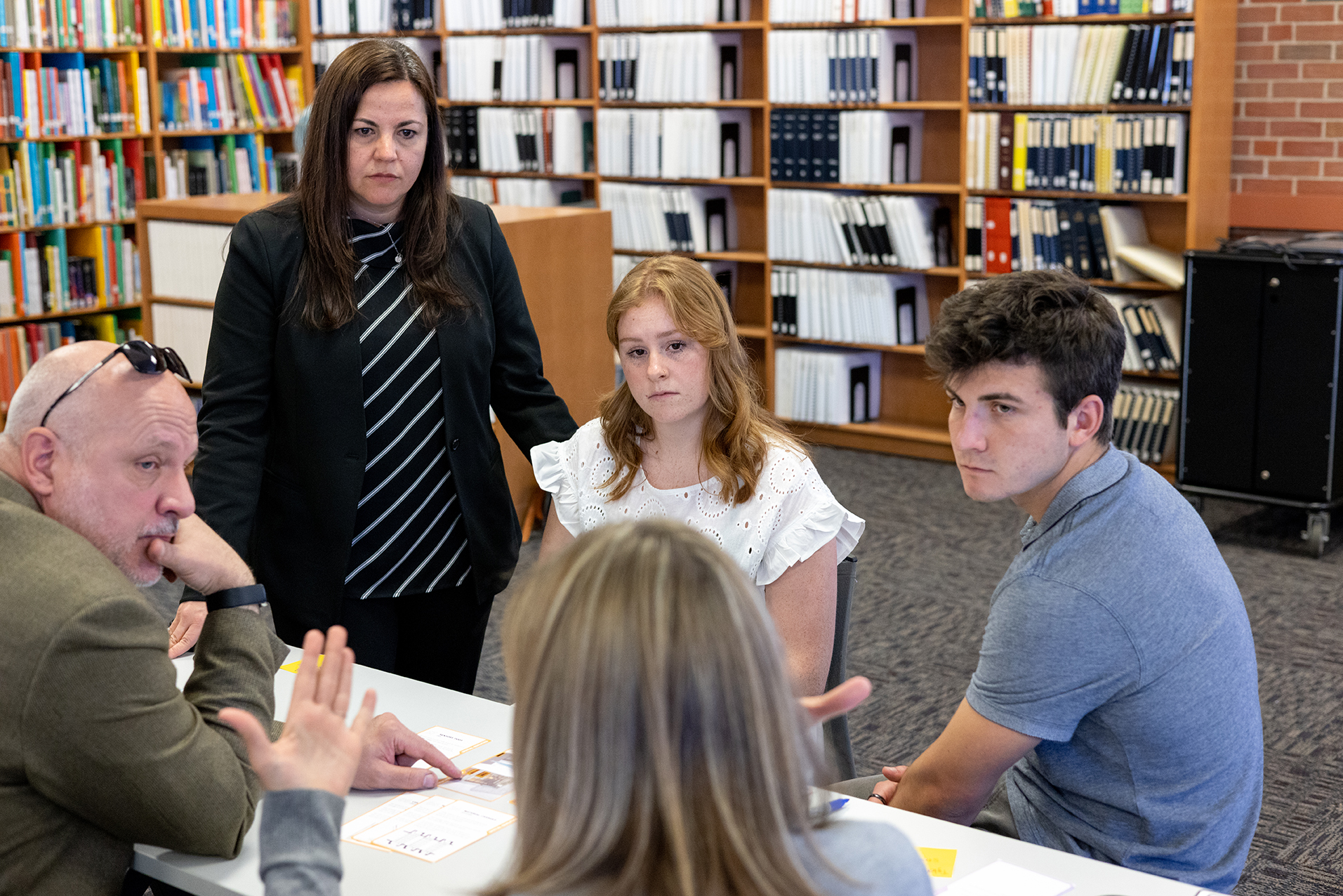 A faculty member instructs students in a library.