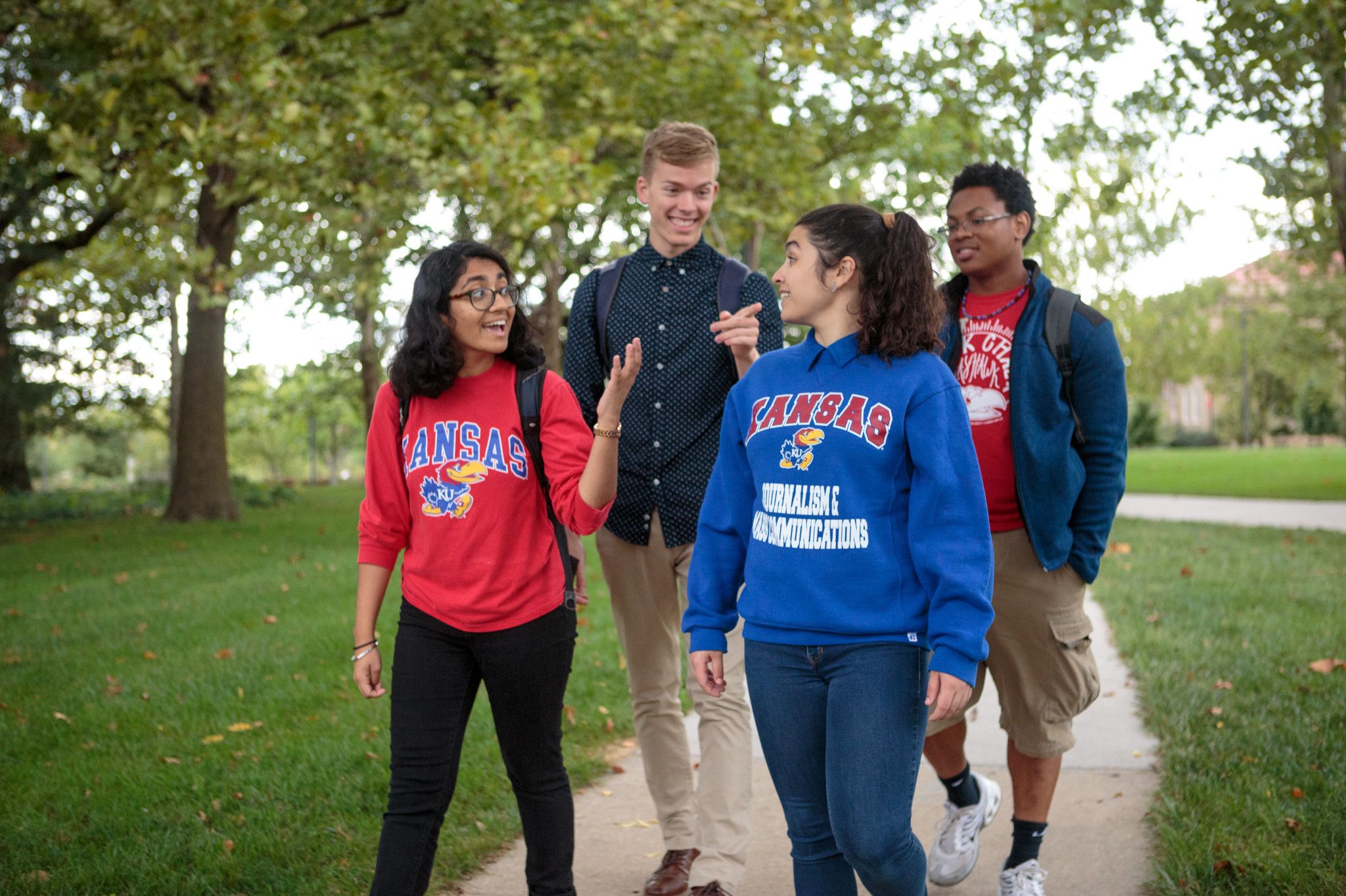 Four students walking on a campus sidewalk.