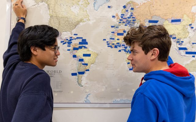 Two students looking at a map of the world.
